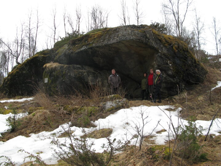 Stort berg midt i bildet. Noe snø foran på en gul bakke. Hvit himmel over og bak.