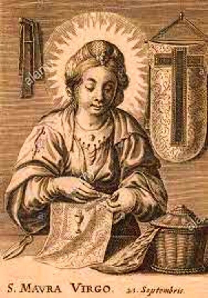 «Et illustrert religiøst motiv som viser en helgenfigur med glorie, sittende ved et bord og arbeider med et stykke stoff. I bakgrunnen henger et korsformet banner og en kurv står ved siden av bordet. Bildet har et gammelt, sepiafarget preg.»