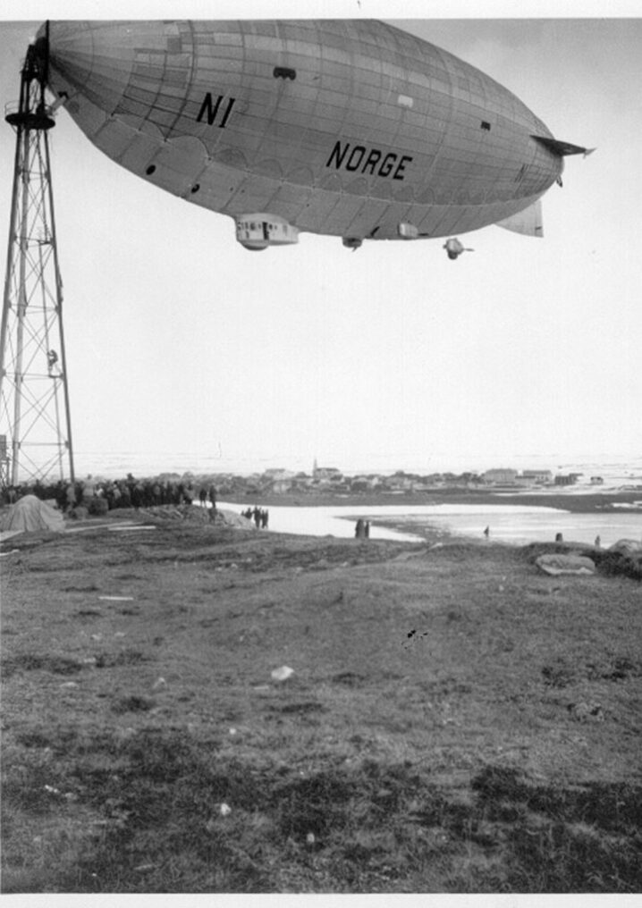 Svart hvitt bilde med gresslette og en luftskipmast med et luftskip