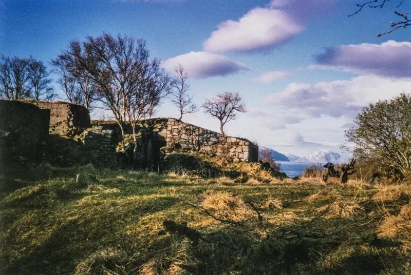 Ruin av et fort midt i bildet. Vegetasjon rundt. Noen trær rundt. Blå himmel med noen skyer.