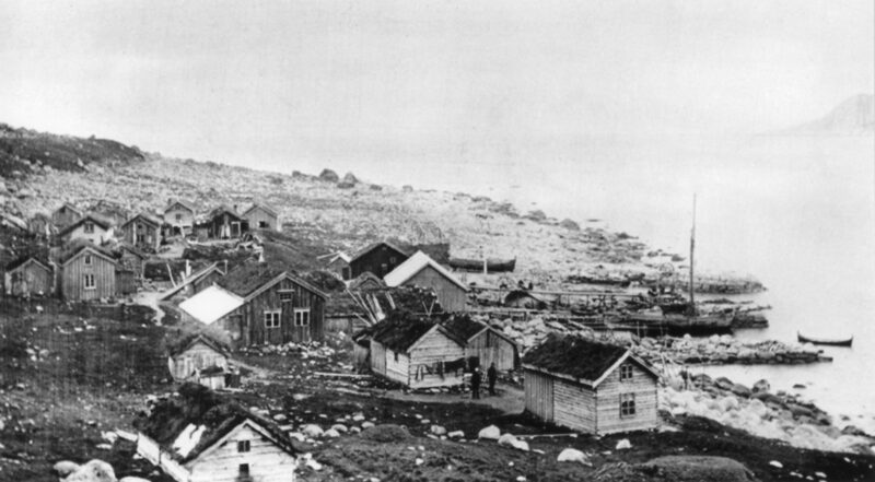 Svart hvitt bilde. Fiskevær ved fjorden.